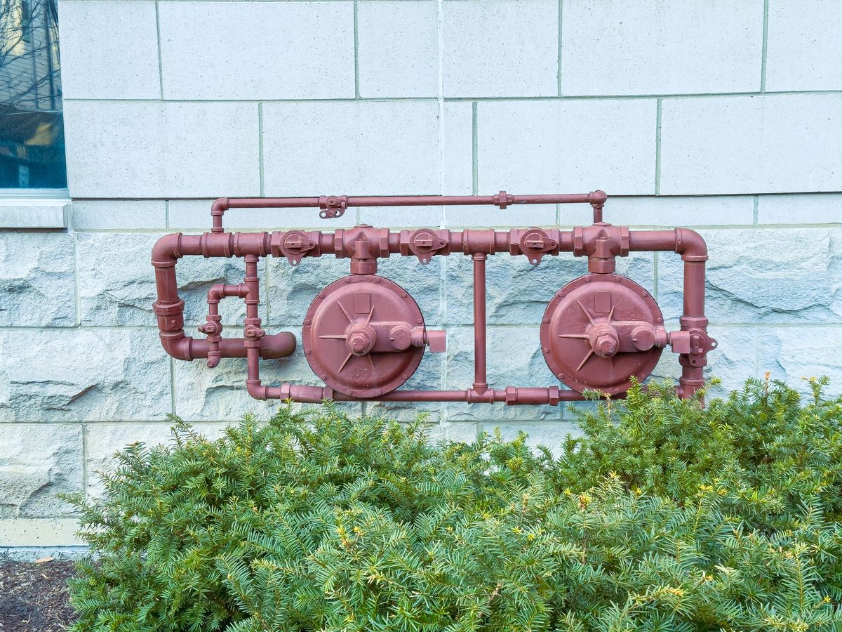 Painted valve and pipe assembly mounted on the outside wall of a building